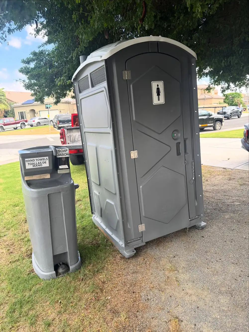 Porta potty and hand-wash station on a lawn