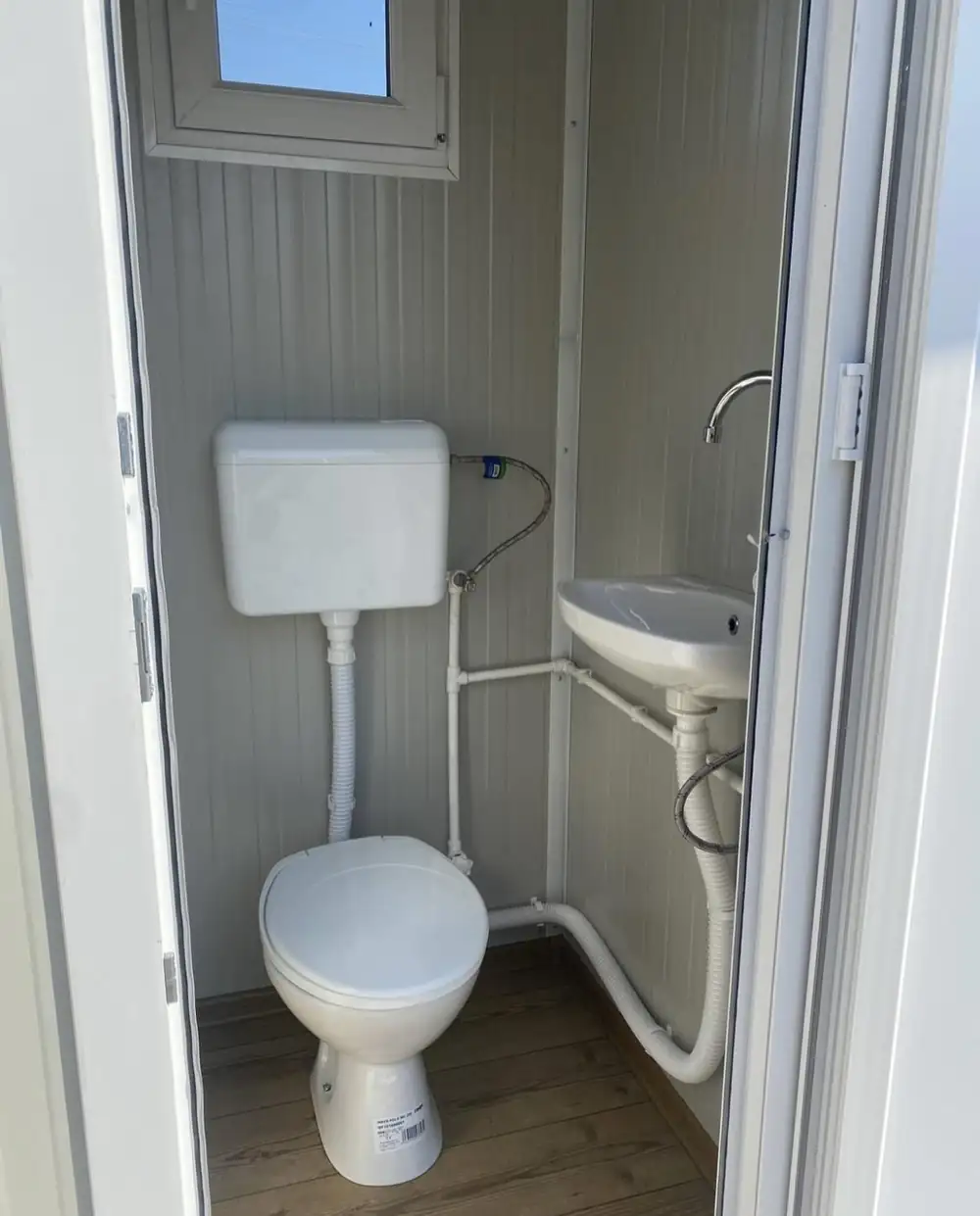 Inside a deluxe flushing cabin with toilet and corner sink