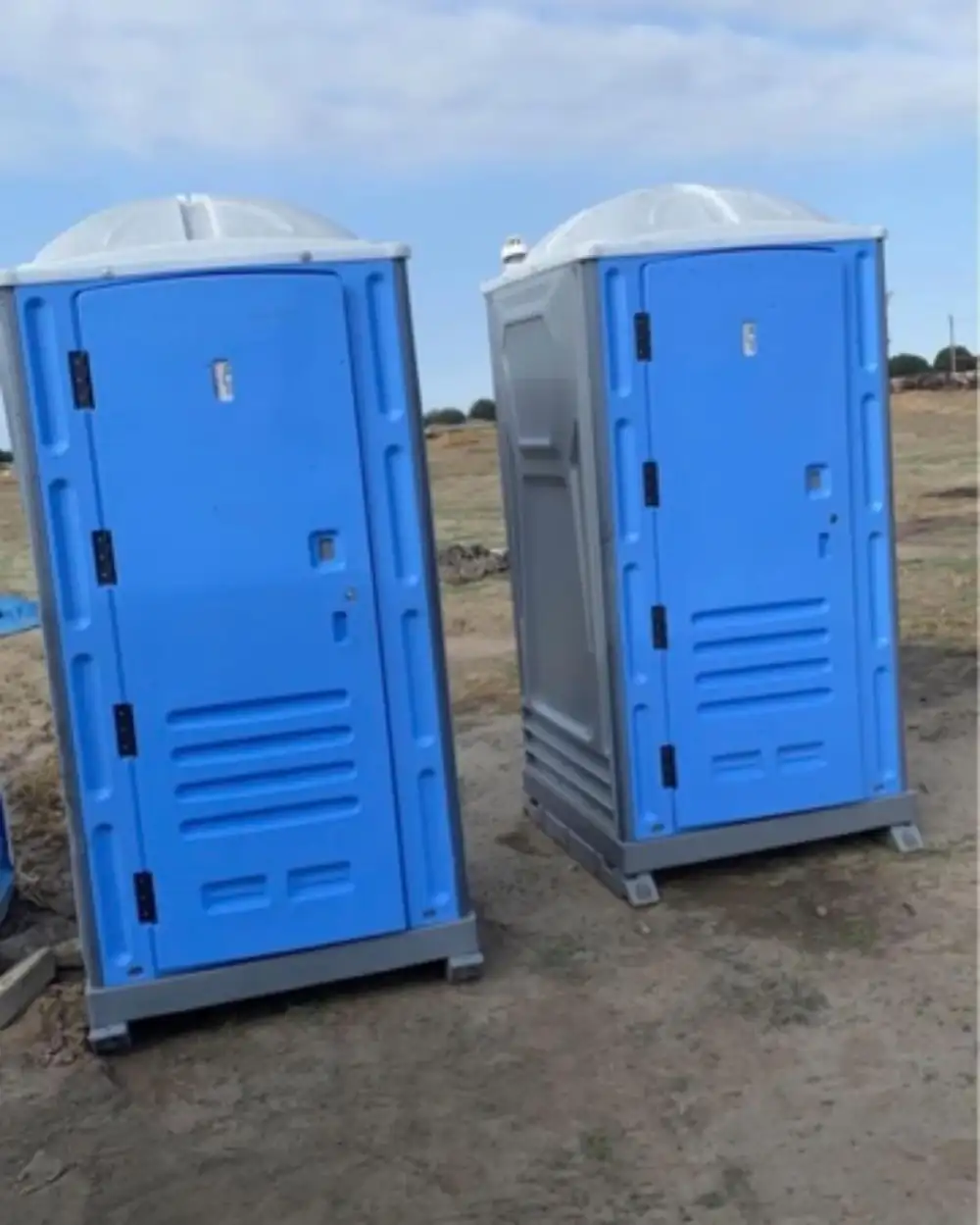 Two blue standard porta potties set on a cleared lot, ready for a Temple job site crew