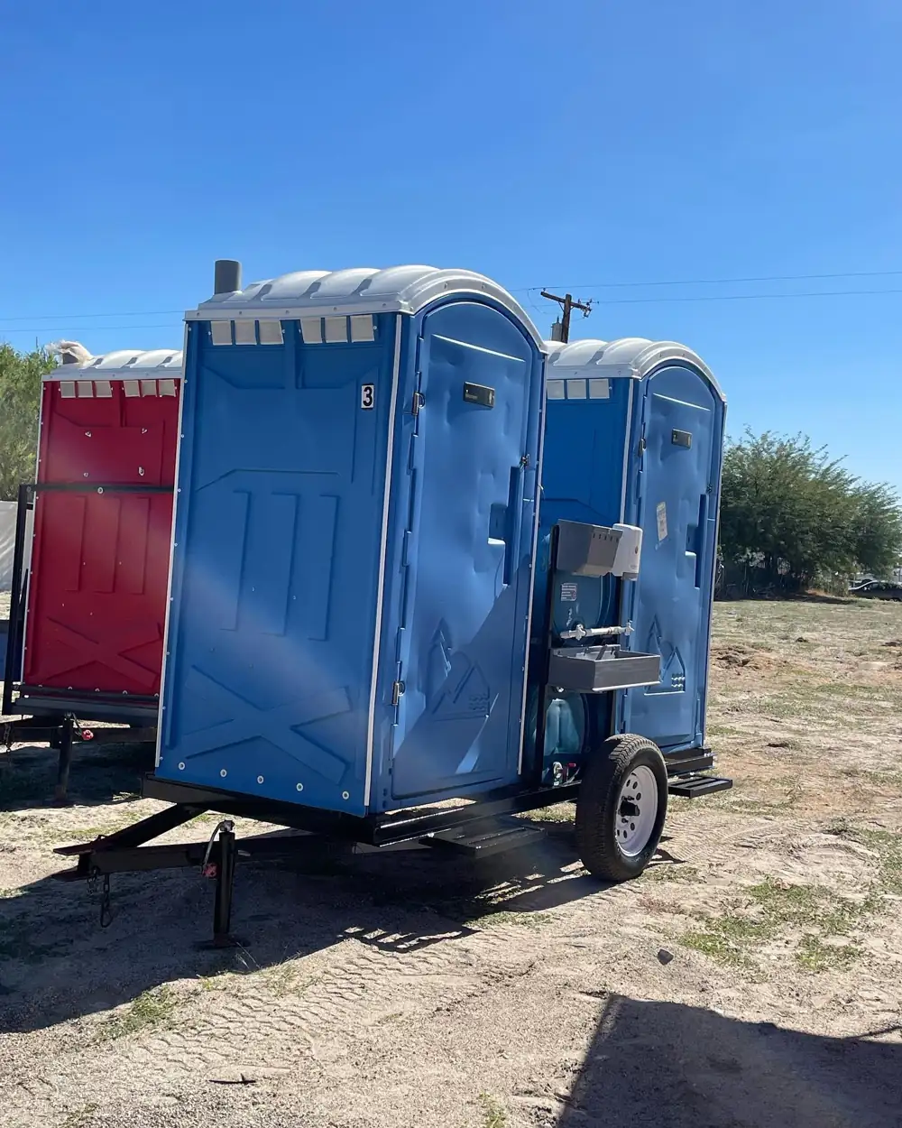 Trailer-mounted porta potty parked at an open construction lot
